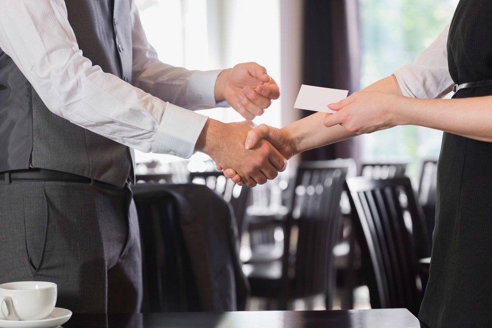 Business people shaking hands after meeting and changing cards in restaurant.jpeg